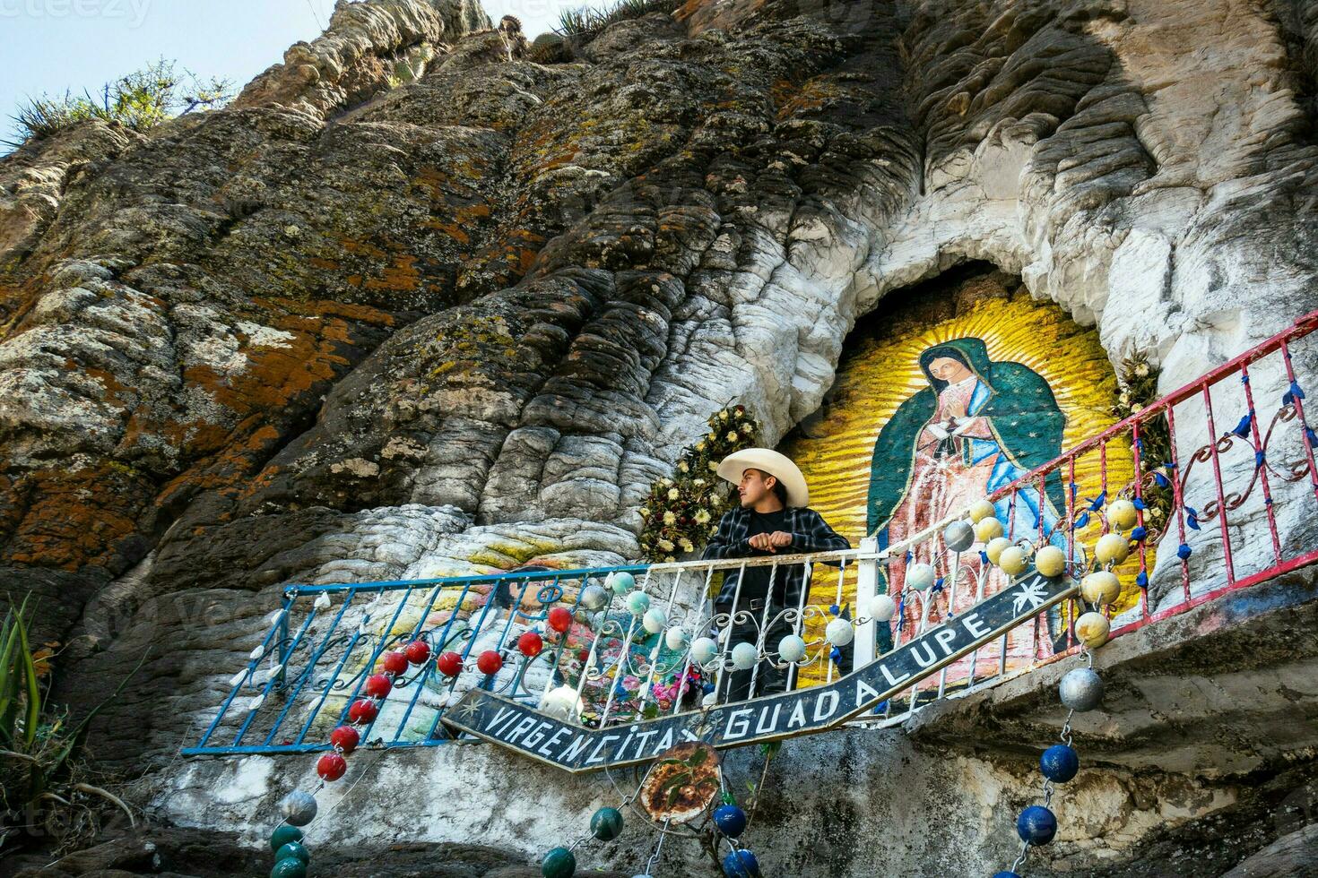 Man visiting virgin of guadalupe painting on rocks in mexico photo