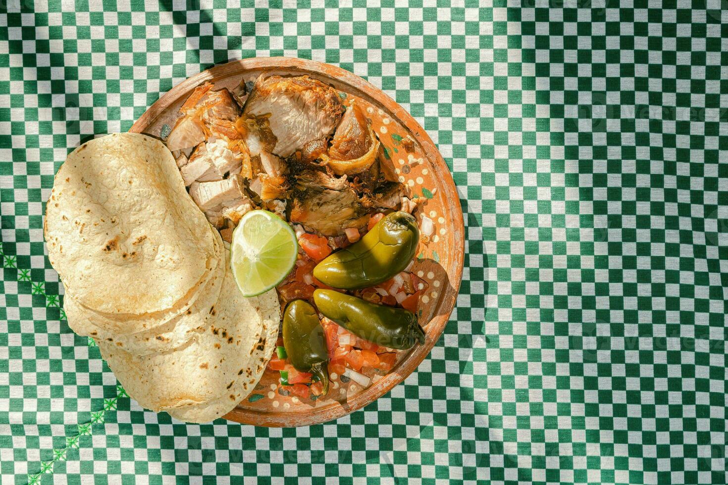 el mexicano Carnitas plato es servido en un mesa, adornado con vajilla y Manteles foto