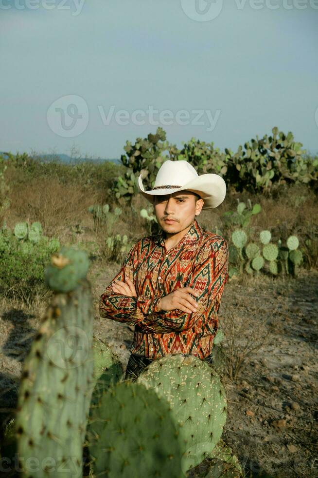 joven hombre con mexicano sombrero en un Desierto paisaje con cactus foto