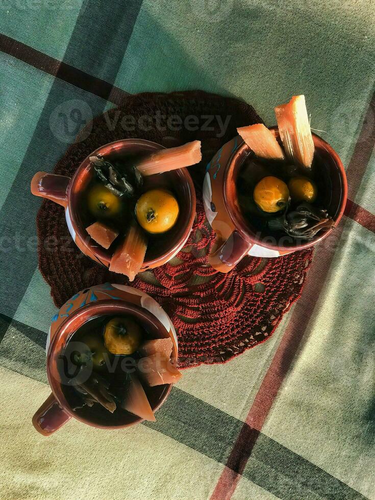 A delightful bowl of Mexican ponche, featuring cane and tejocote, served on wooden tableware photo