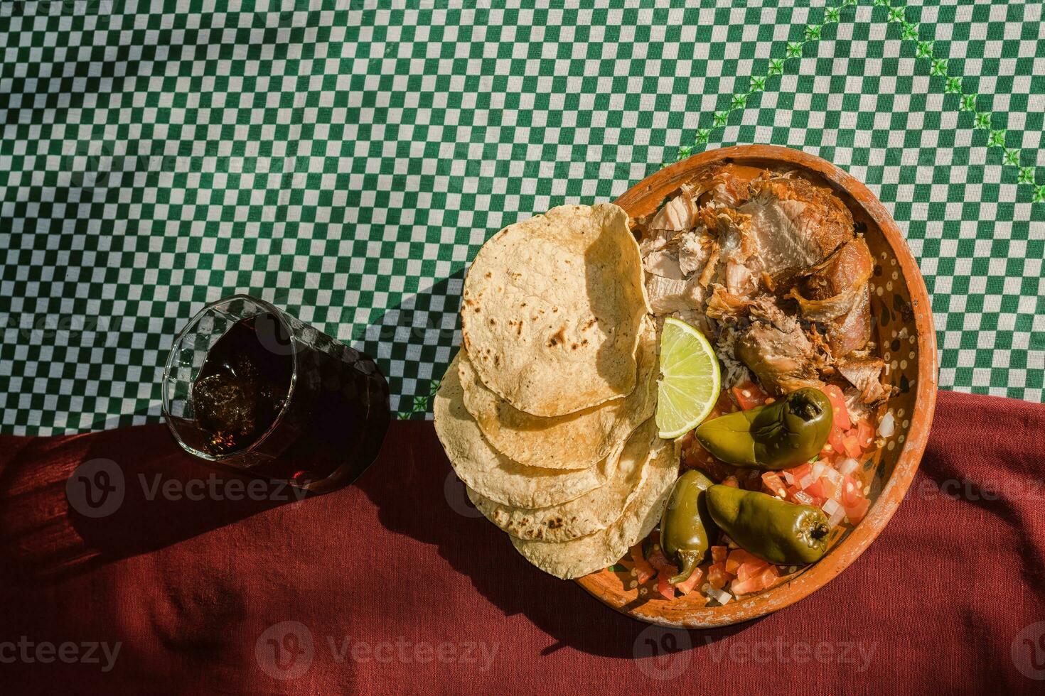 The Mexican carnitas, a delicious food, is served with various condiments on a table with tableware photo