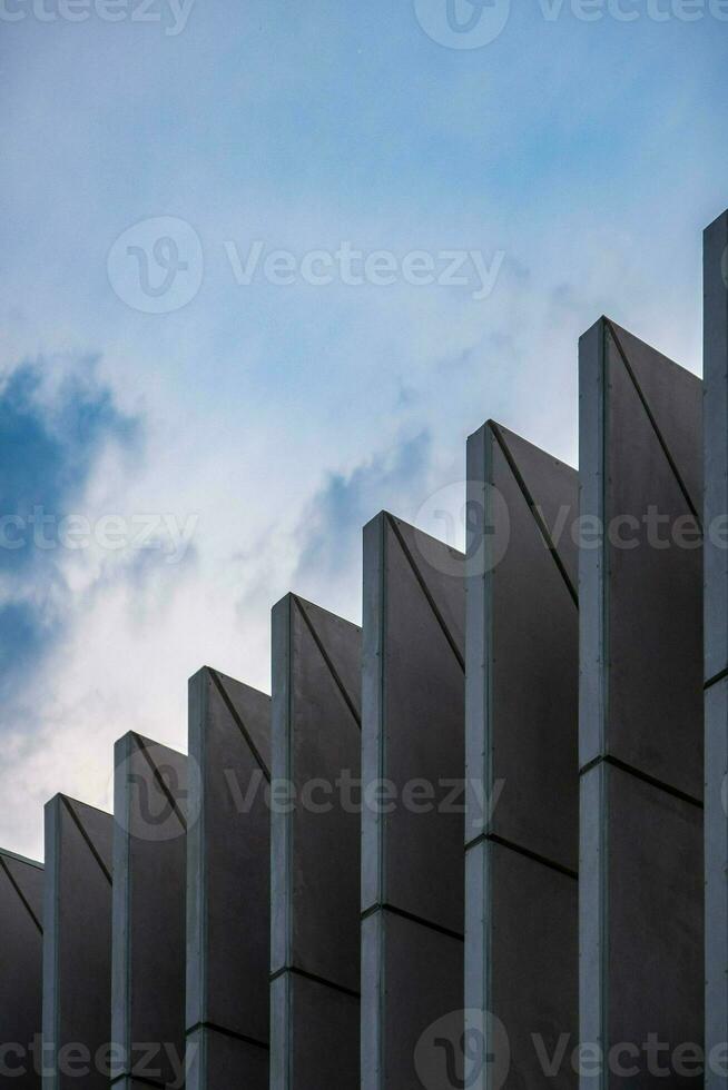 Towering skyscraper with a composite facade, reflecting clouds, nature, and urban design. photo