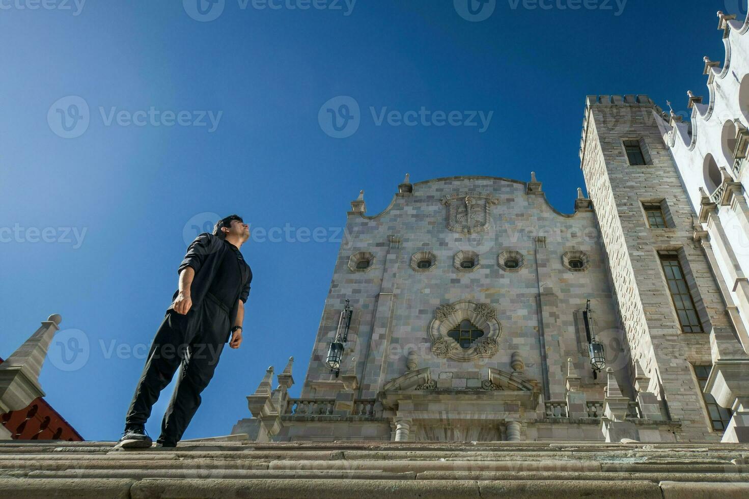 A student exploring the lively streets of Guanajuato, Mexico, with the iconic university building in the background photo