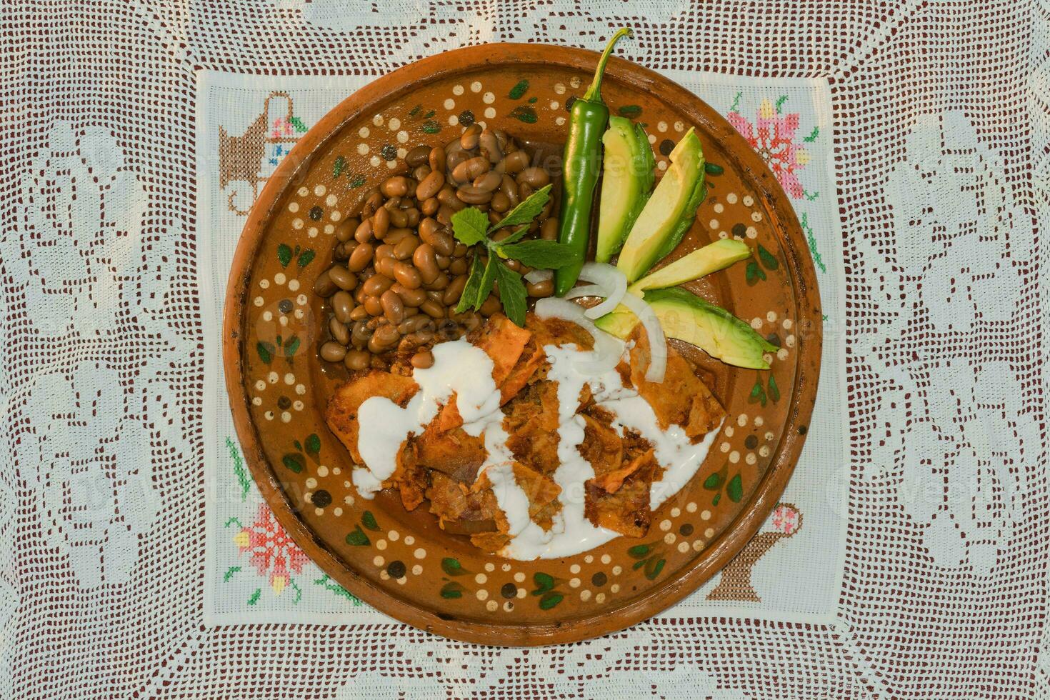 In Mexico, traditional chilaquiles are served on a table with colorful dishware and fresh ingredients. photo