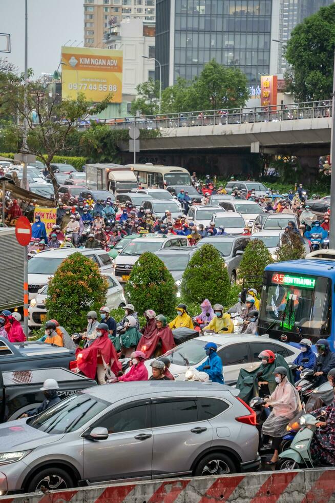 Ho Chi Minh, Viet Nam - 24 April 2023 Vietnamese people wear helmet and raincoat ride motorbike in heavy rain and traffic jam. photo