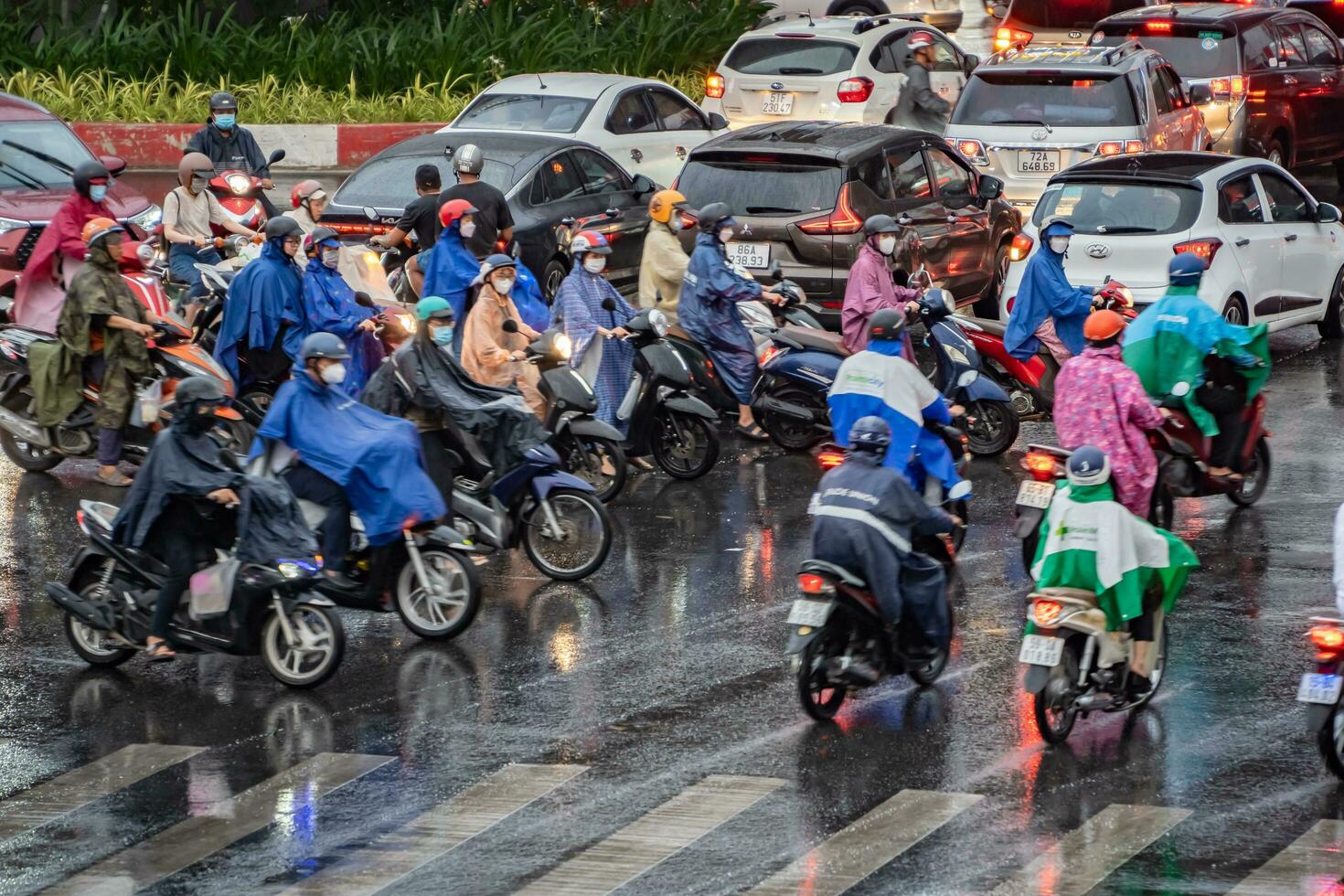 Ho Chi Minh, Viet Nam - 24 April 2023 Vietnamese people wear helmet and raincoat ride motorbike in heavy rain and traffic jam. photo