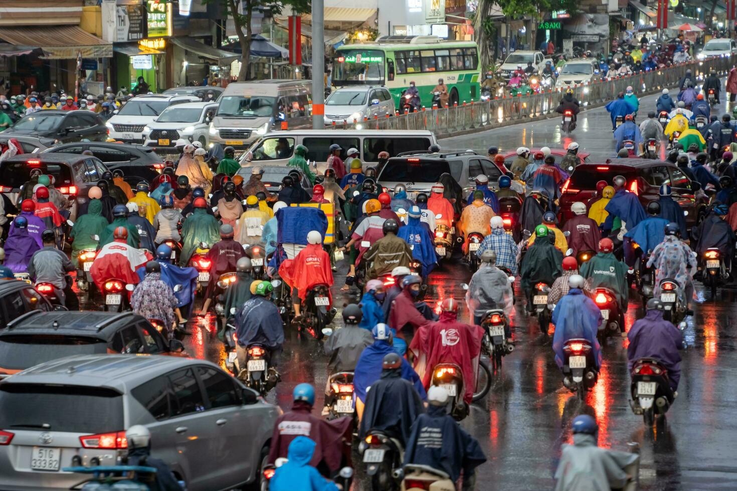 Ho Chi Minh, Viet Nam - 24 April 2023 Vietnamese people wear helmet and raincoat ride motorbike in heavy rain and traffic jam. photo