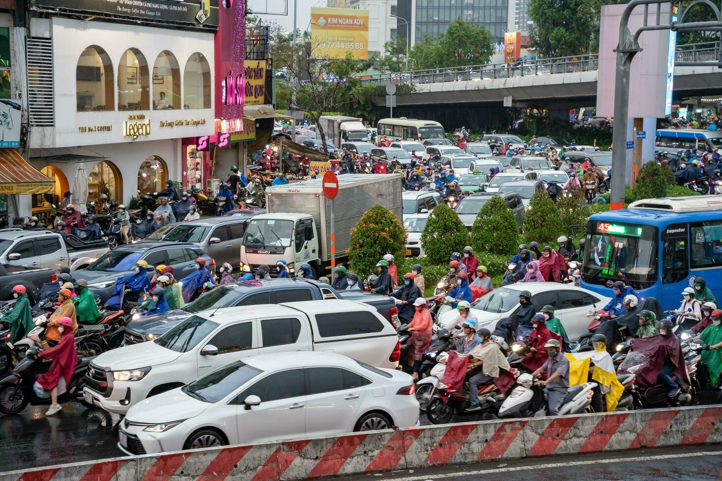 Ho Chi Minh, Viet Nam - 24 April 2023 Vietnamese people wear helmet and raincoat ride motorbike in heavy rain and traffic jam. photo