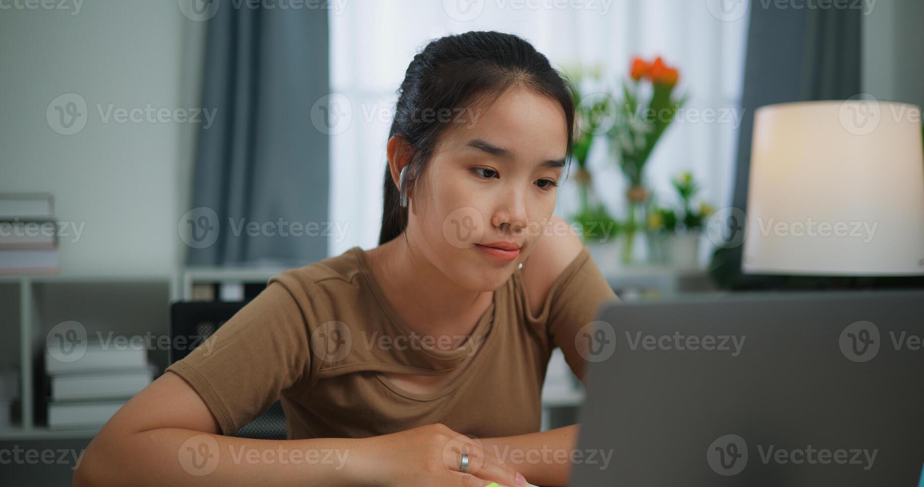 Tired young Asian woman working with laptop photo