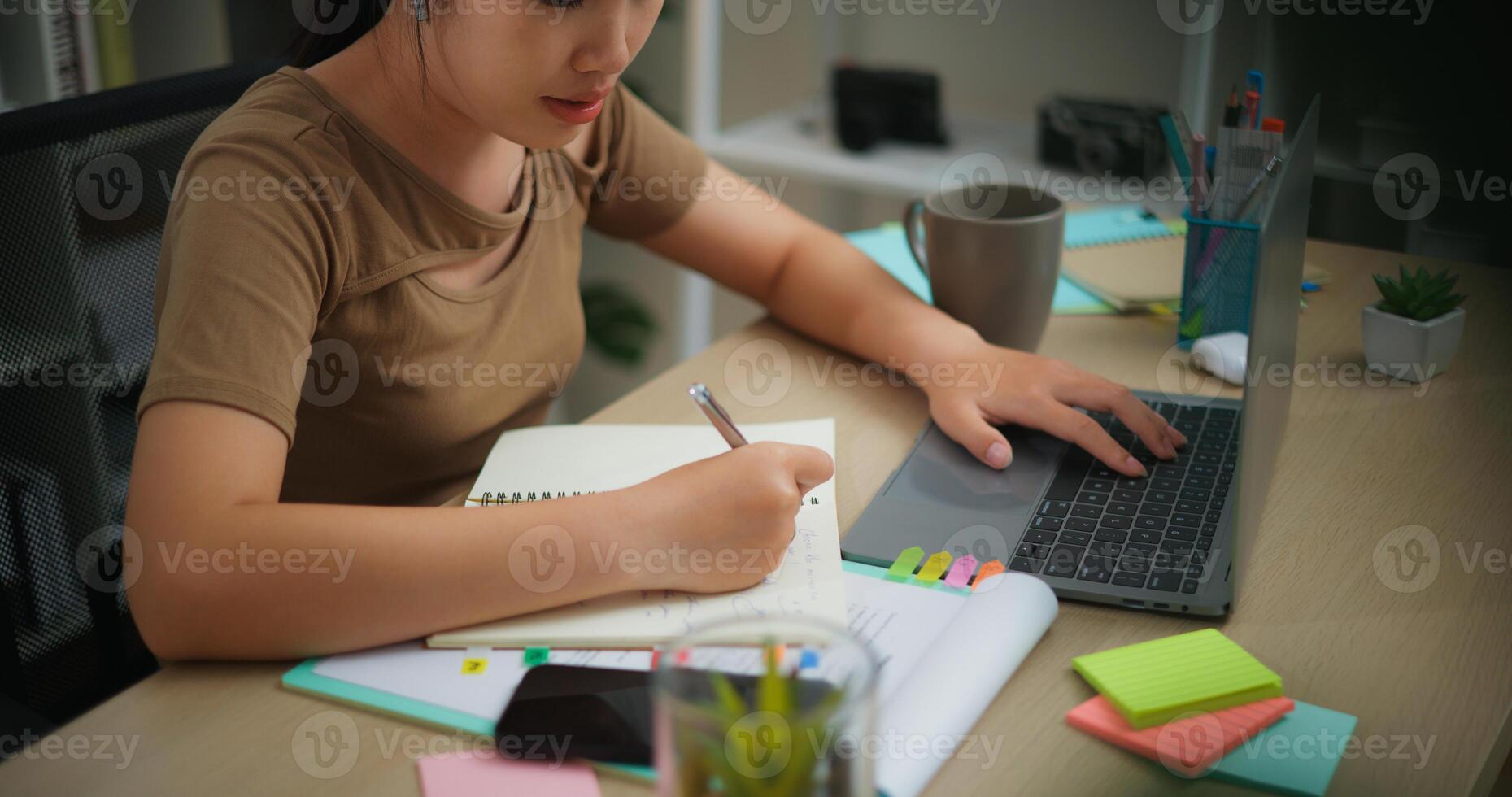 joven asiático mujer trabajando con un ordenador portátil y escritura en papel en un escritorio foto