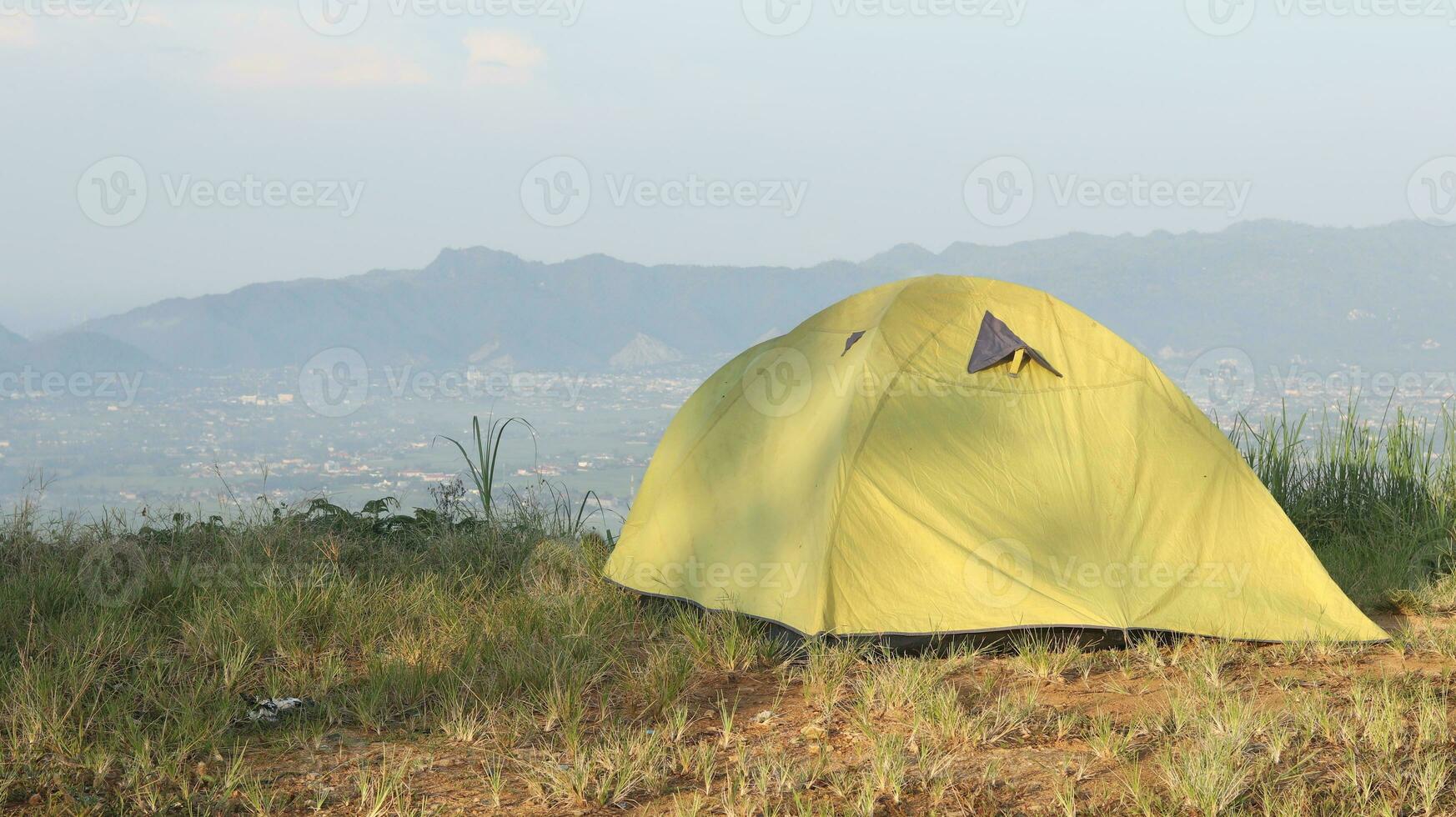 Camping tent on a hill with mountains in the background in the morning photo