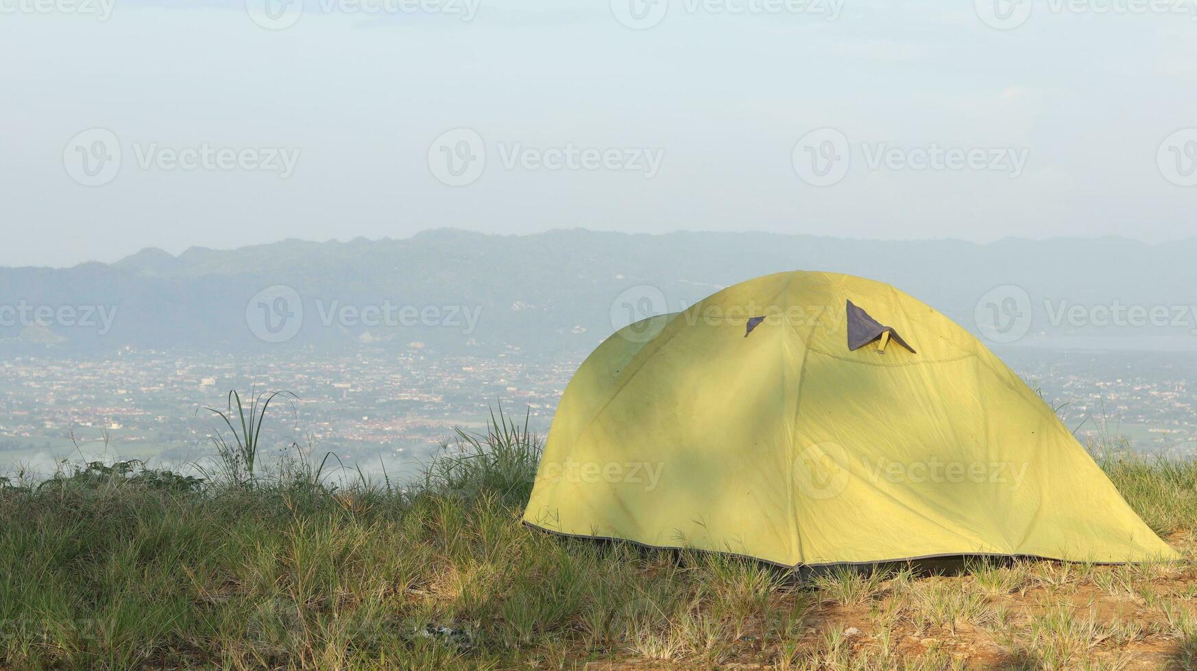 Camping tent on a hill with mountains in the background in the morning photo