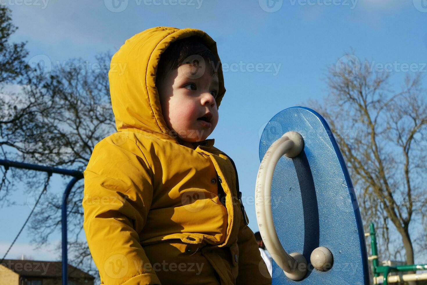 Cute Asian Pakistani Baby is Enjoying Beautiful Sunny and Cold Day at Lewsey Public Park of Luton Town of England UK. Low Angle  Image Was Captured on April 03rd, 2023 photo