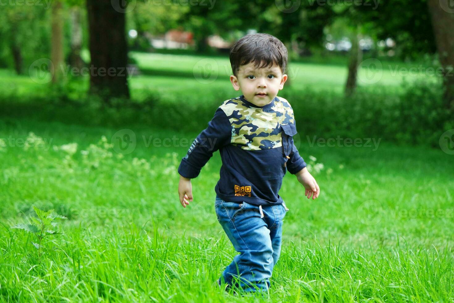 Cute Asian Pakistani Baby is Enjoying The Beautiful Sunny Day at Wardown Children and Public Park of Luton Town of England UK. Low Angle  Image Was Captured on April 03rd, 2023 photo