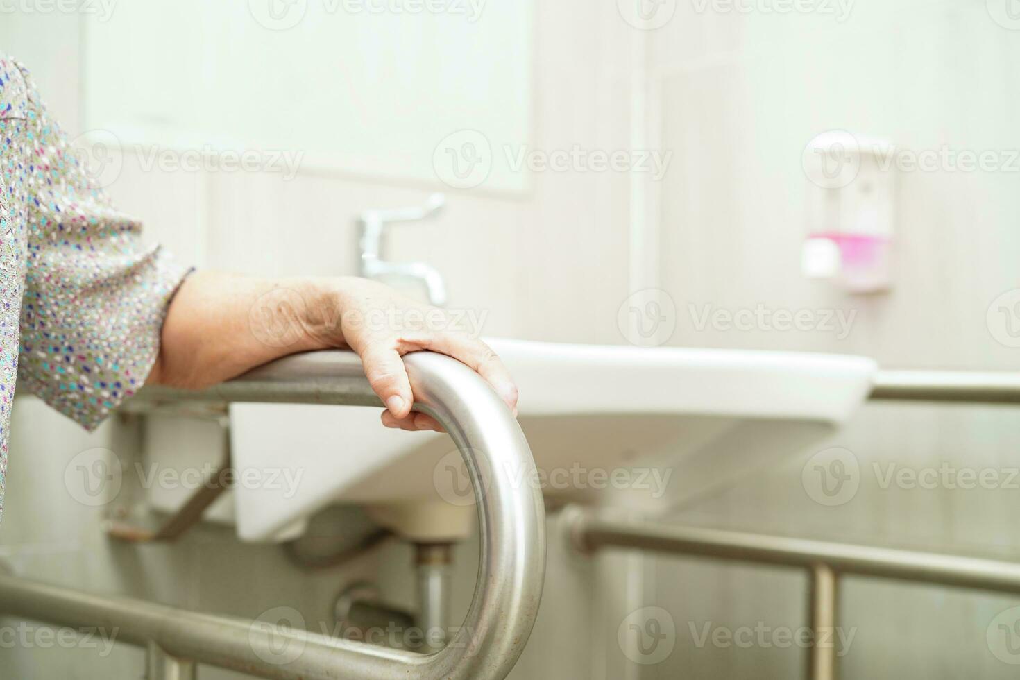 Asian elderly old woman patient use toilet support rail in bathroom, handrail safety grab bar, security in nursing hospital. photo