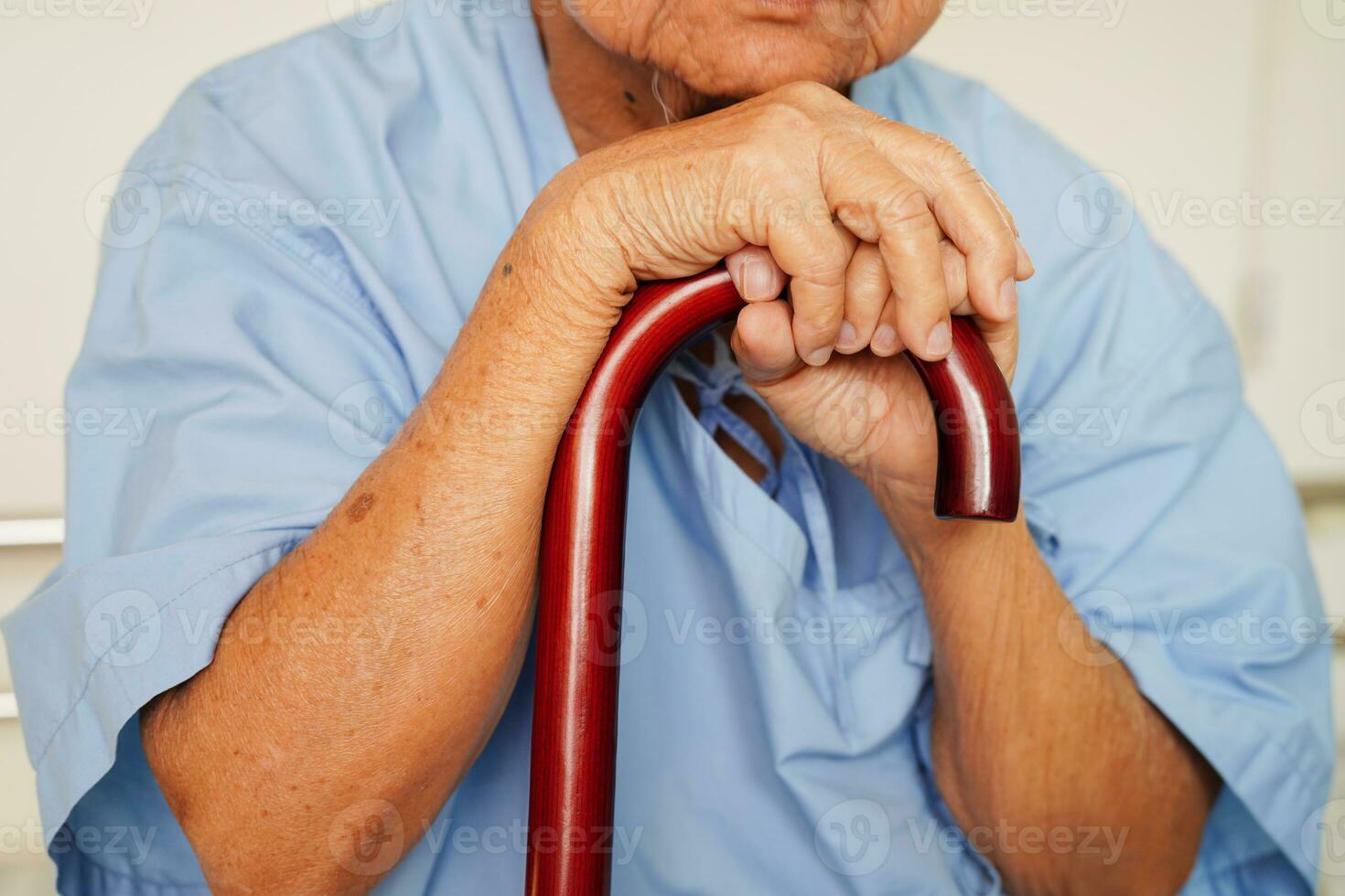 Asian elderly disability woman patient holding walking stick in wrinkled hand at hospital. photo