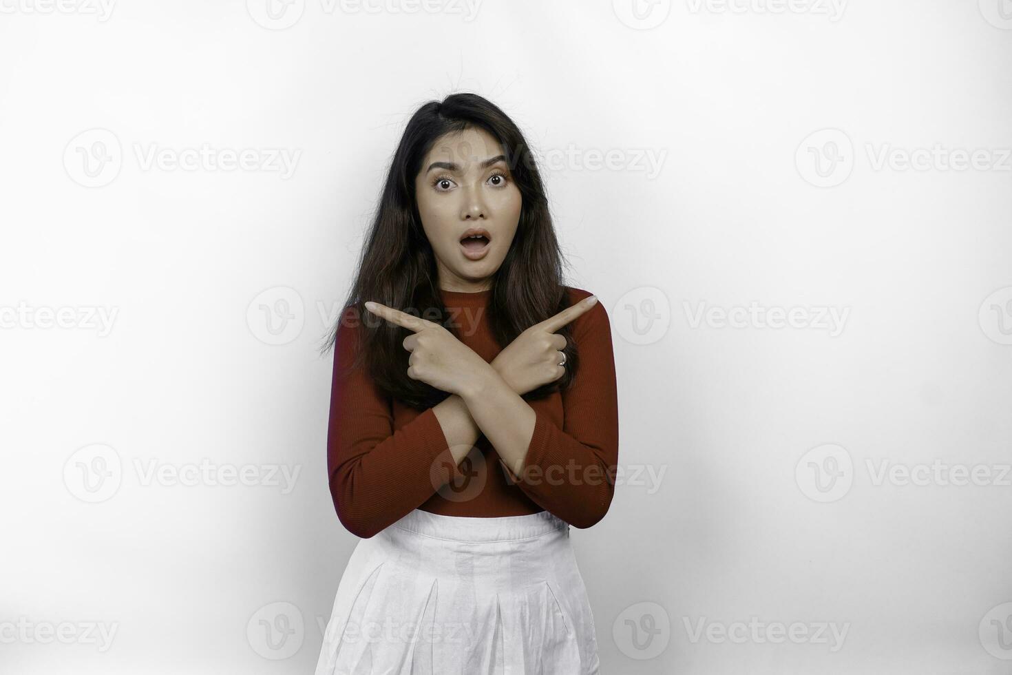 Shocked Asian woman wearing red t-shirt, pointing at the copy space on beside her, isolated by white background photo