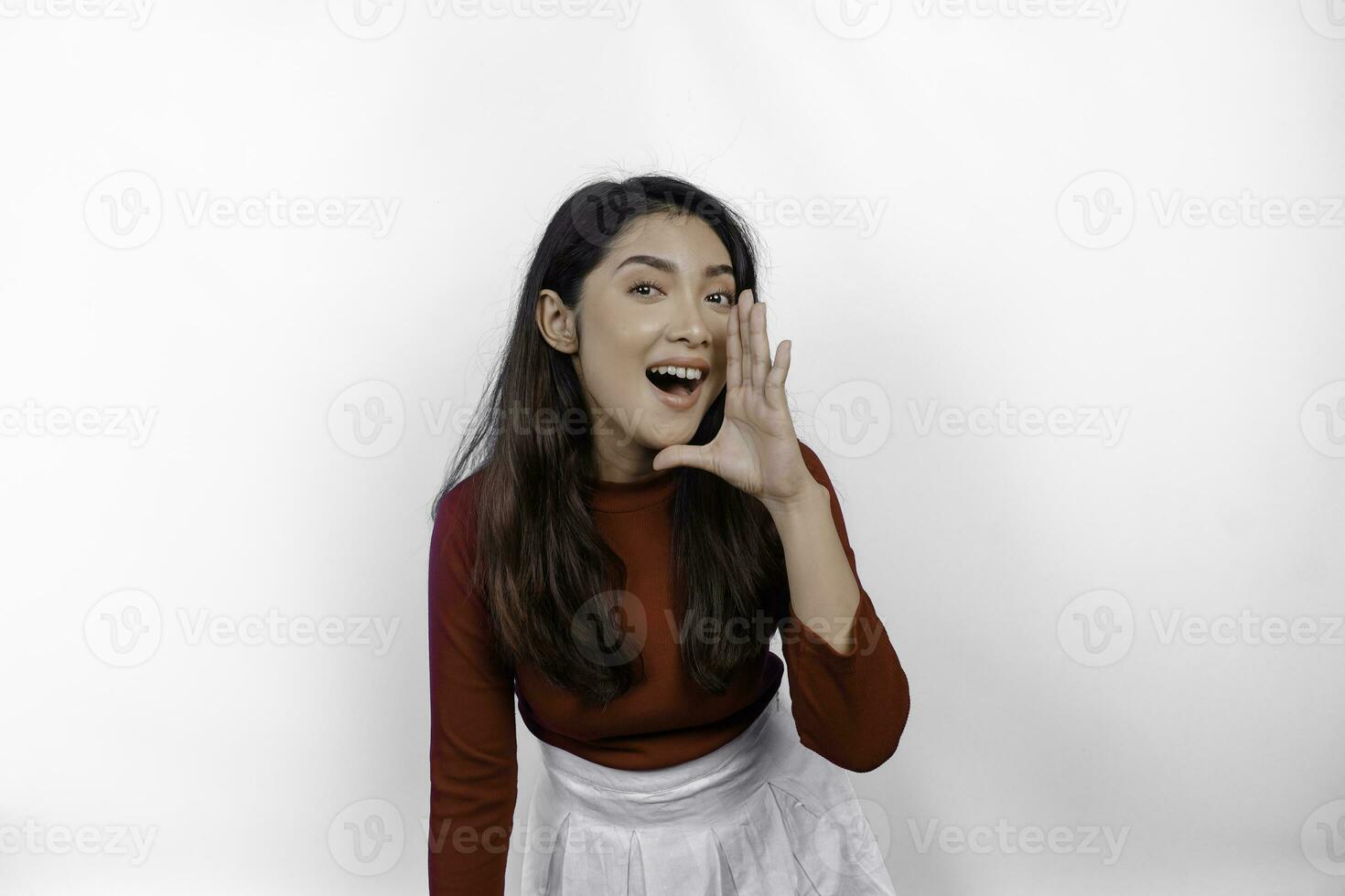 Young beautiful woman wearing a red top shouting and screaming loud with a hand on her mouth. communication concept. photo