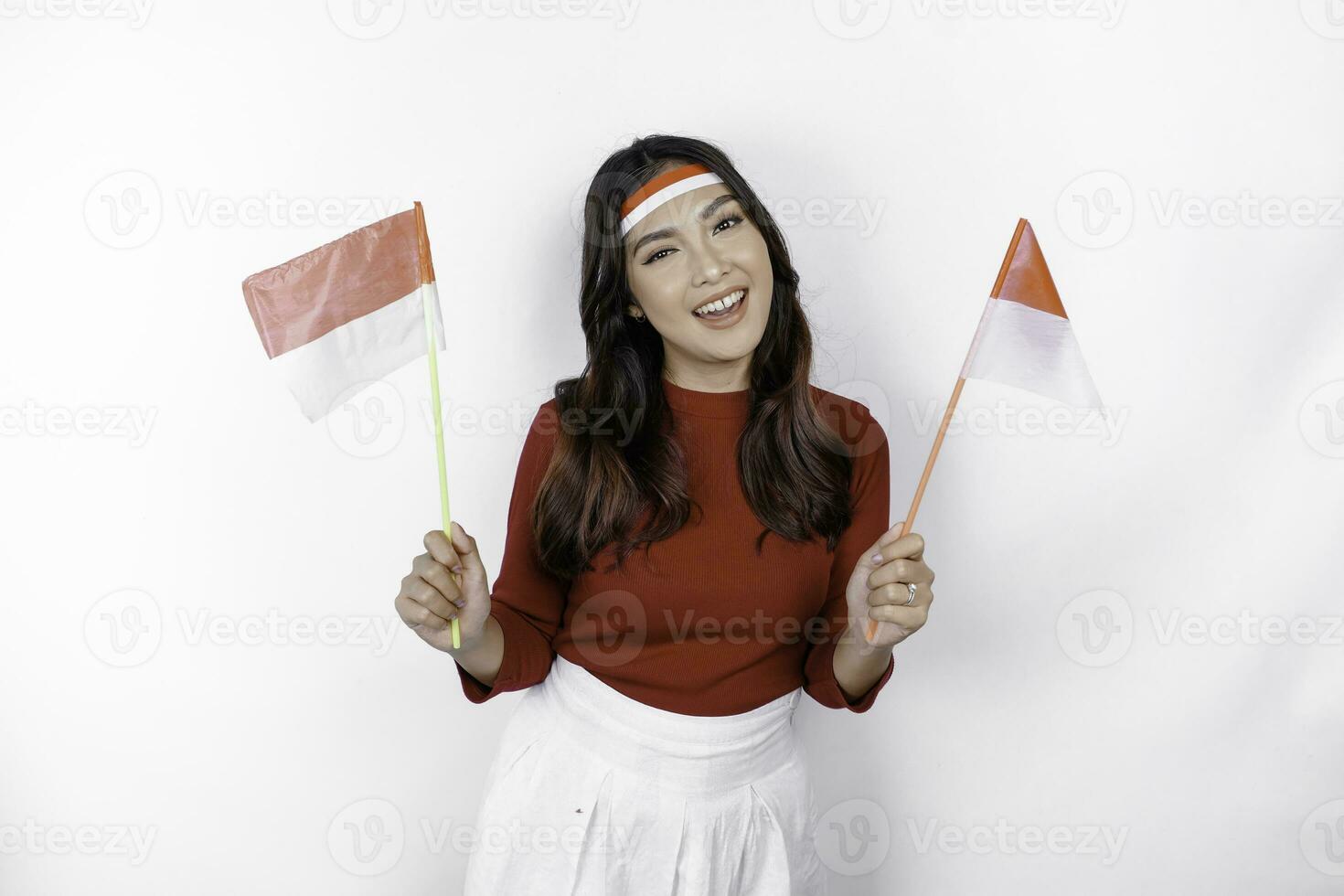 Excited young Asian woman celebrate Indonesian independence day holding the Indonesian flag isolated on white background photo