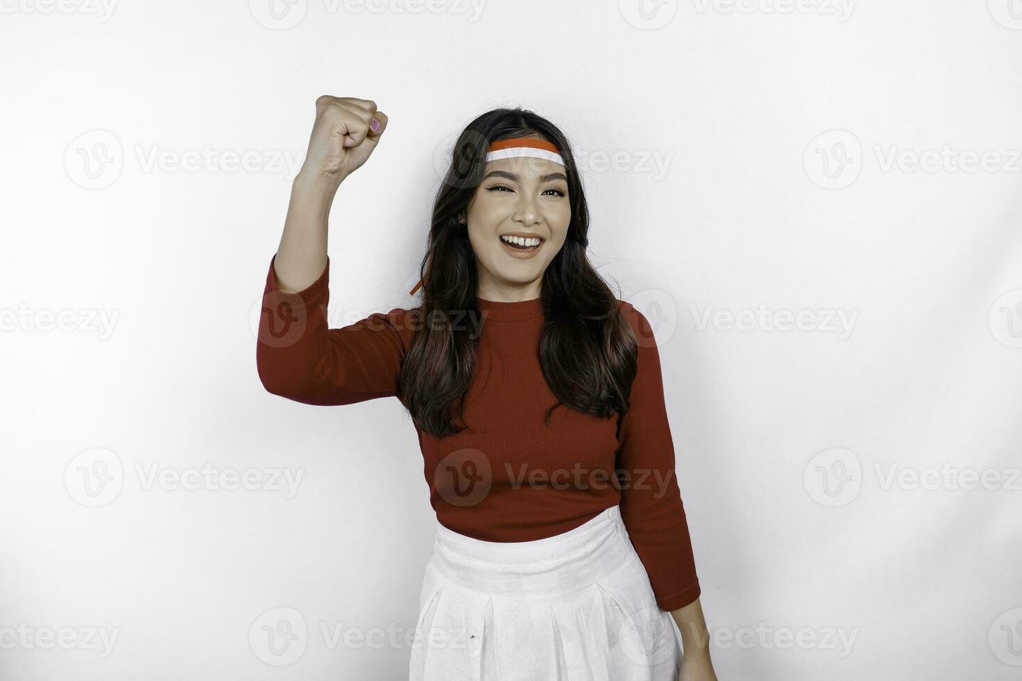 A young Asian woman with a happy successful expression wearing red top and flag headband isolated by white background. Indonesia's independence day concept. photo