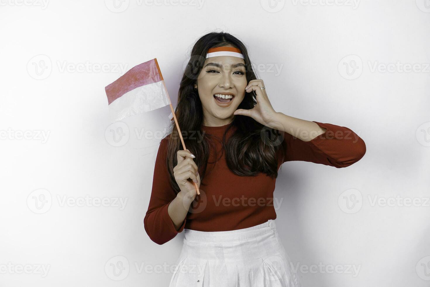 Happy smiling Indonesian woman holding Indonesia's flag and showing love sign to celebrate Indonesia Independence Day isolated over white background. photo