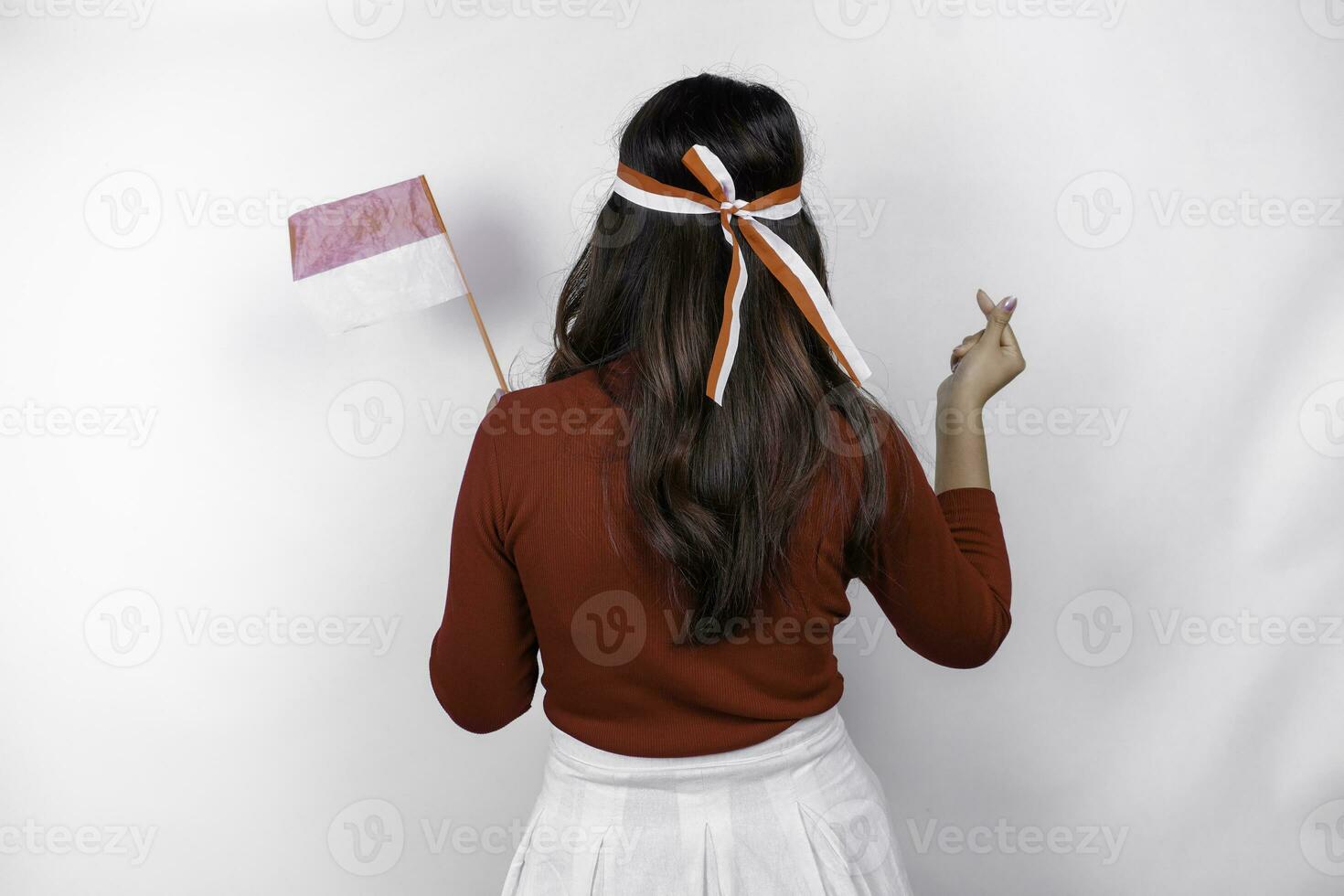 Back view of a young Asian woman wearing a red top feels romantic shapes heart gesture expresses tender feelings photo