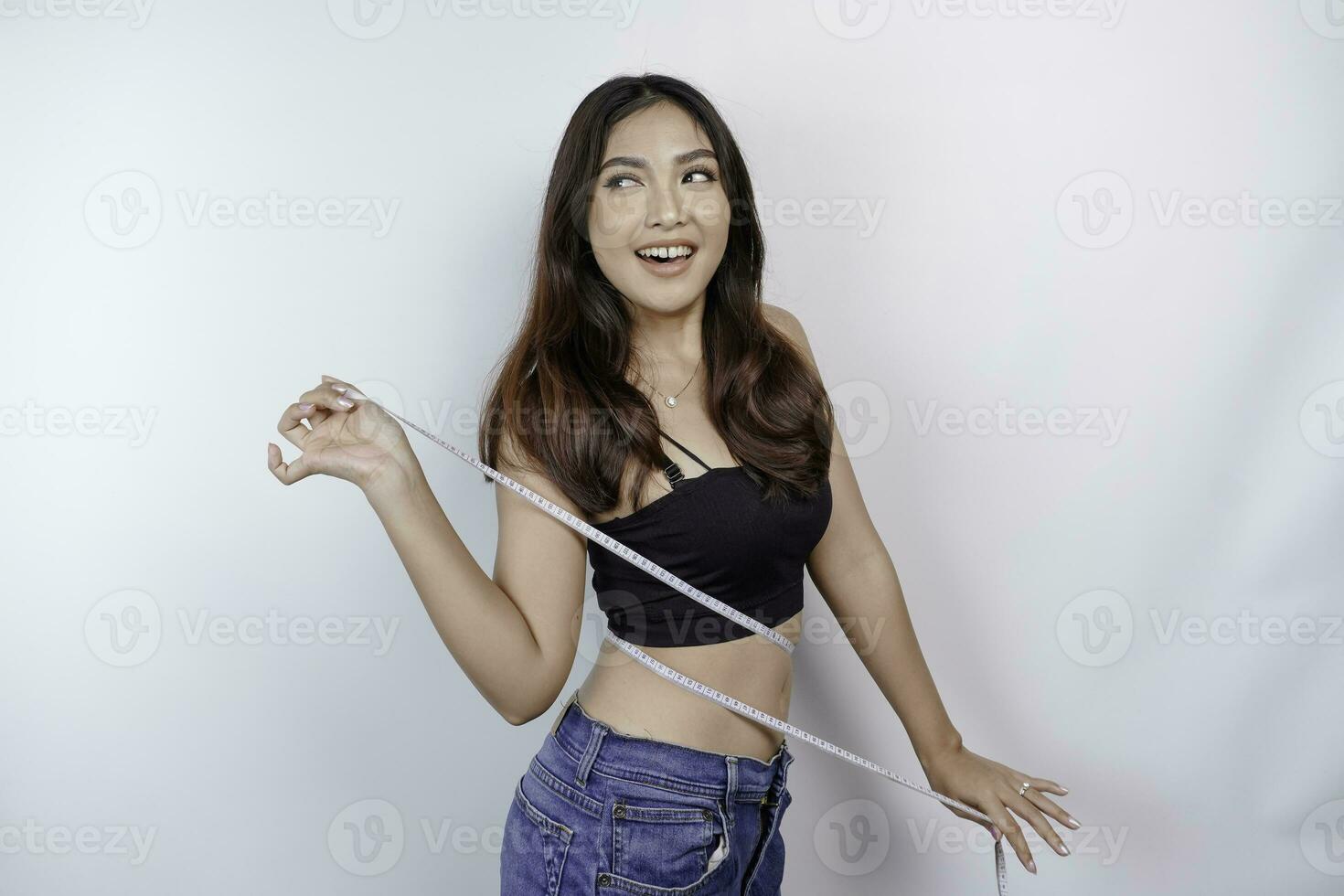 Weight loss, slim body, healthy lifestyle concept. Fit fitness Asian girl measuring her waist with measuring tape, isolated by white background photo