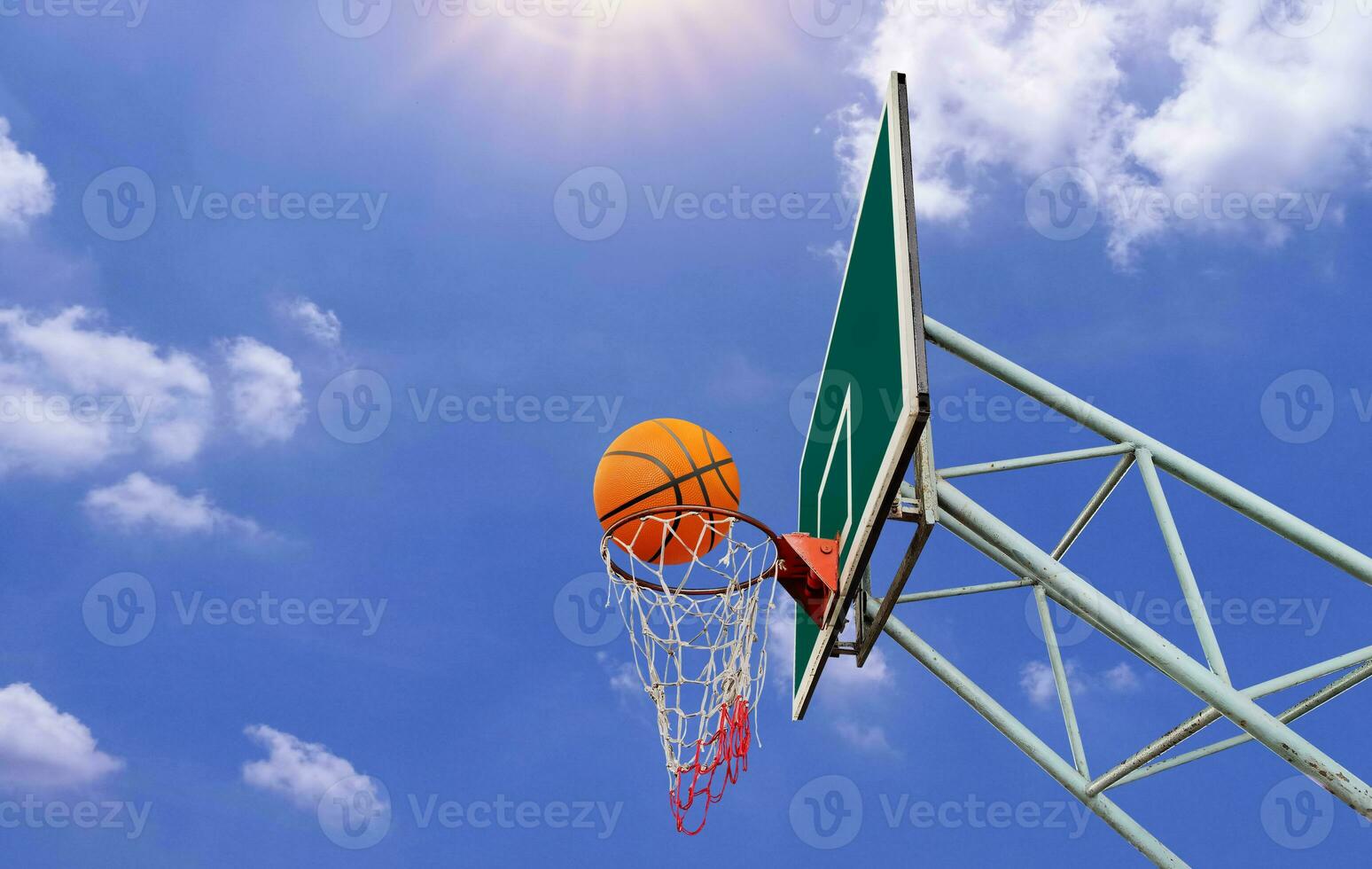 A basketball in a net on a blue sky background. The ball hit the ring. Sports, team game. Conceptual victory, success, hitting the target, sport. photo