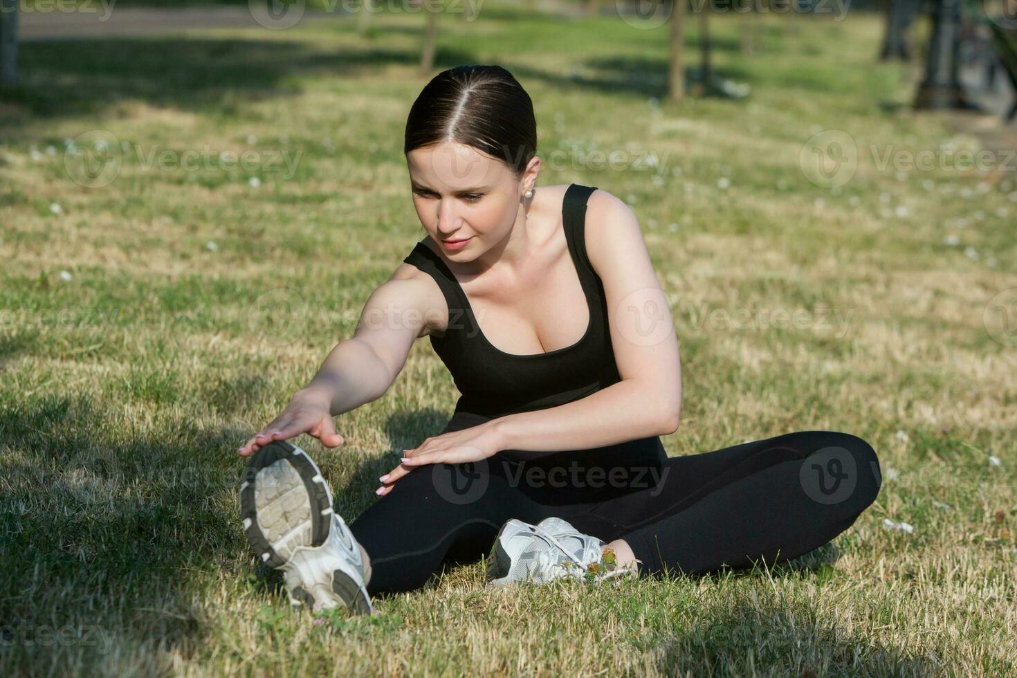 Portrait of smiling young woman in black sportswear exercising outdoors. Fitness and healthy lifestyle concept. photo