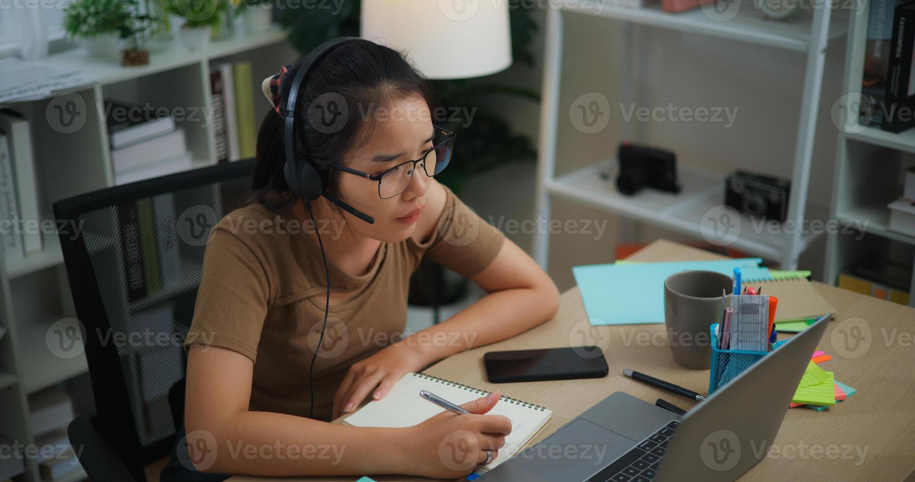 Young Asian woman wearing glasses using a laptop on a desk photo