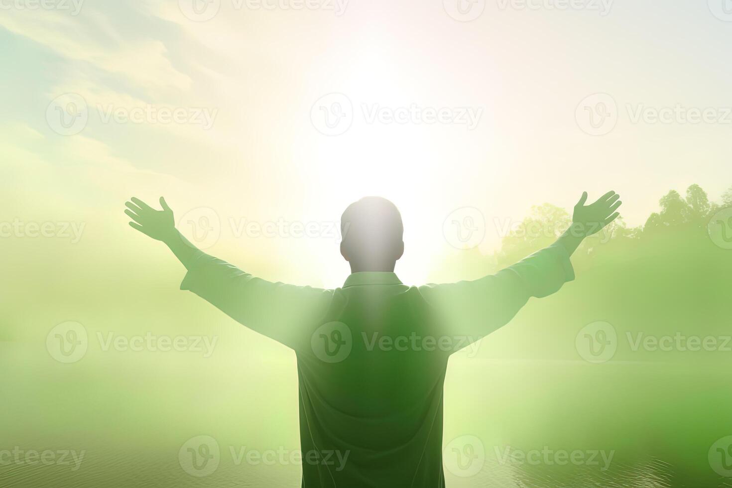 Happy young man standing in a natural sunrise with raising arms. photo