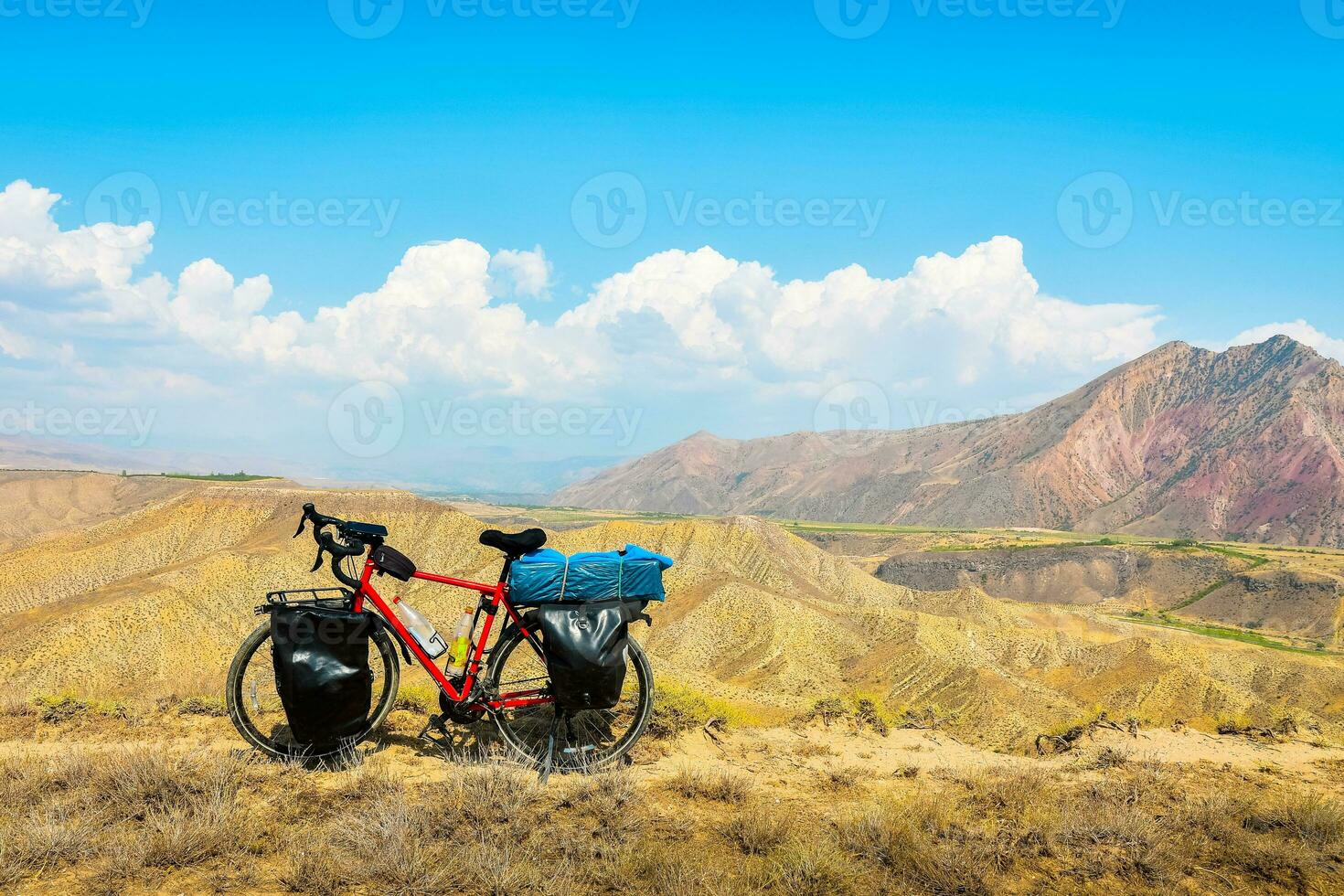 Loaded touring bicycle stands with moody dramatic panoramic mountains view and no cyclist photo