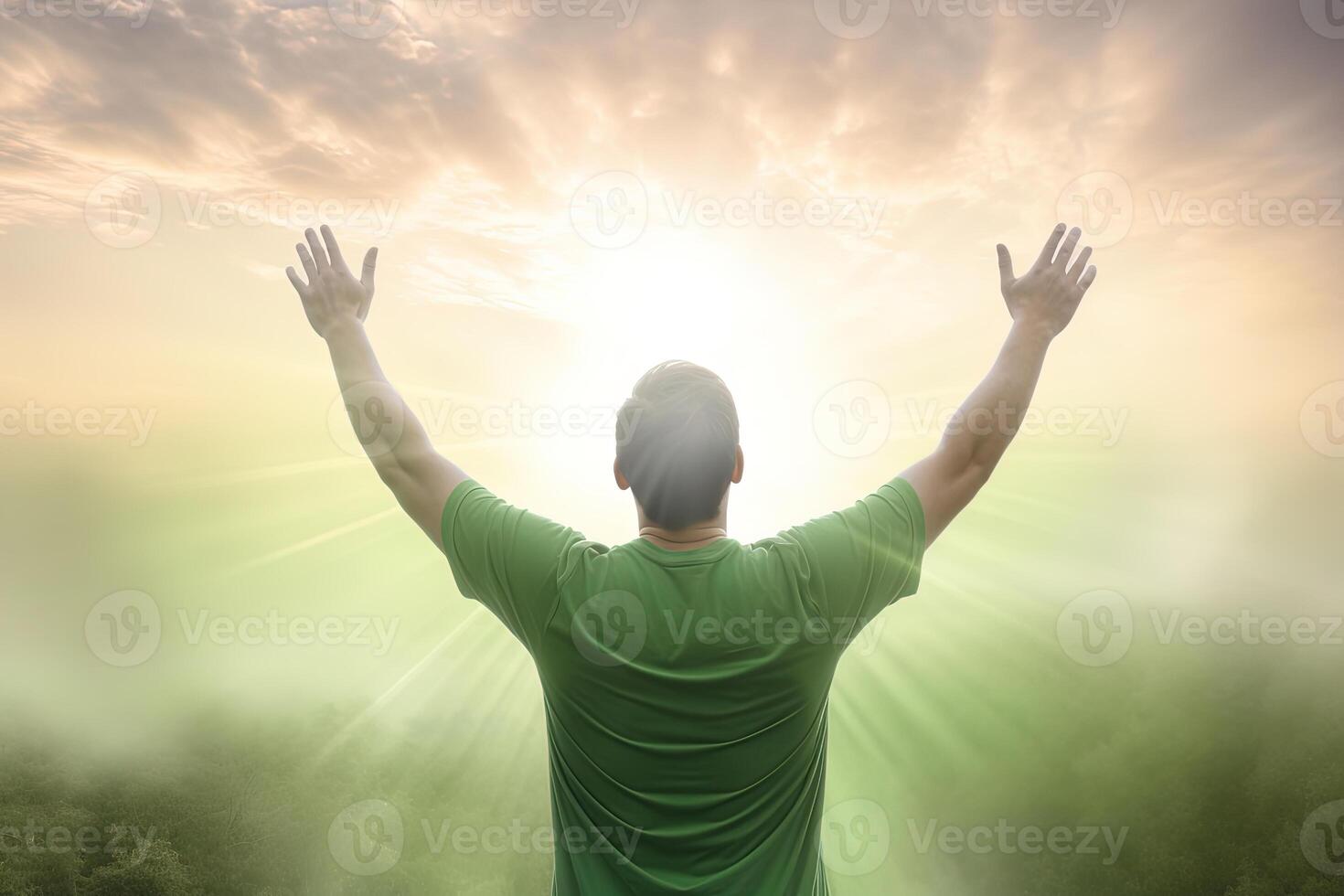 Happy young man standing in a natural sunrise with raising arms. photo