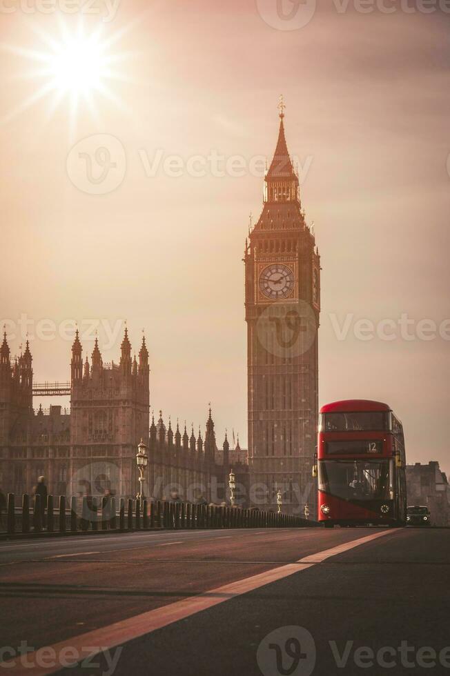 Red London Bus on the Westminster Bridge and Big Ben Tower in the background. photo