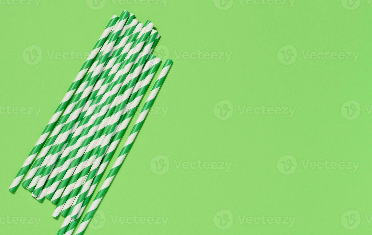 Paper cocktail straws on a green background, top view photo