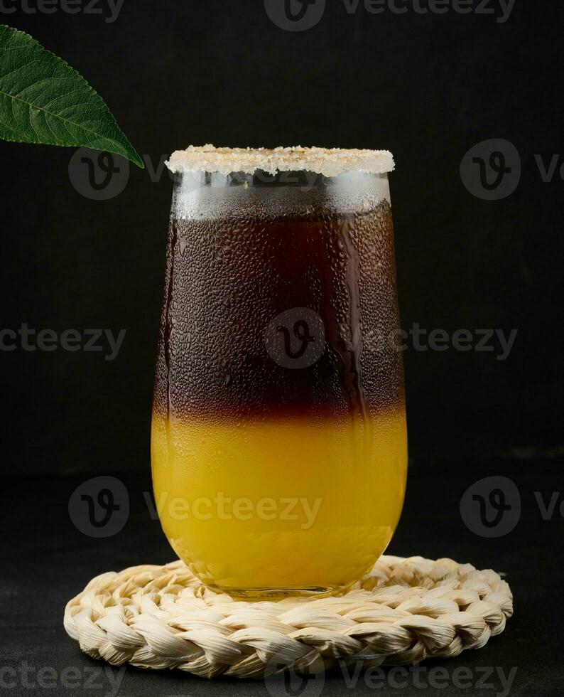 Iced coffee with orange juice in a transparent glass, refreshing bumble coffee on the table, black background photo