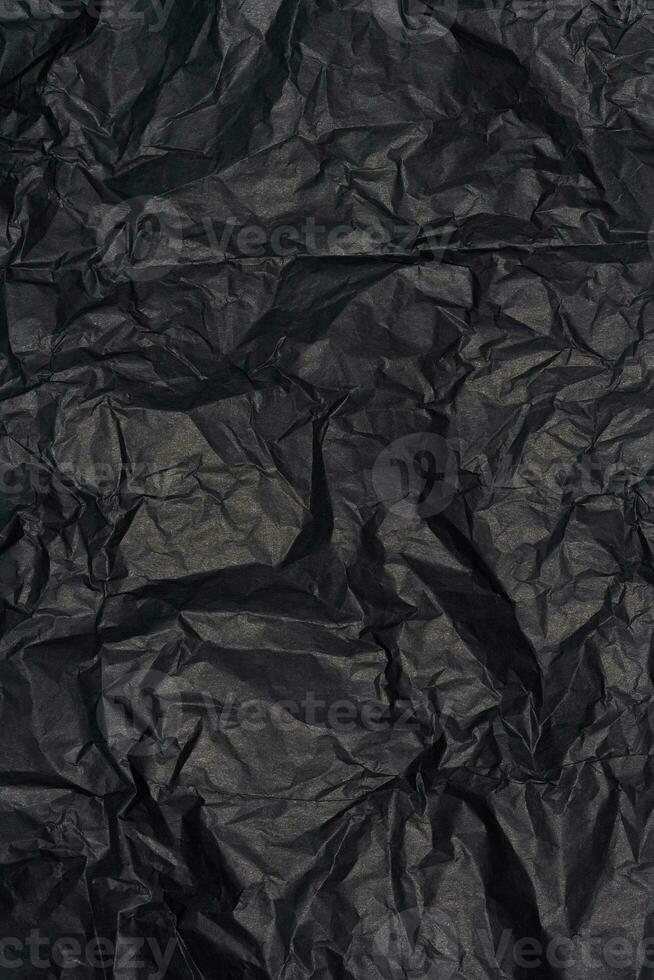 Crumpled sheet of black parchment paper, abstract background photo