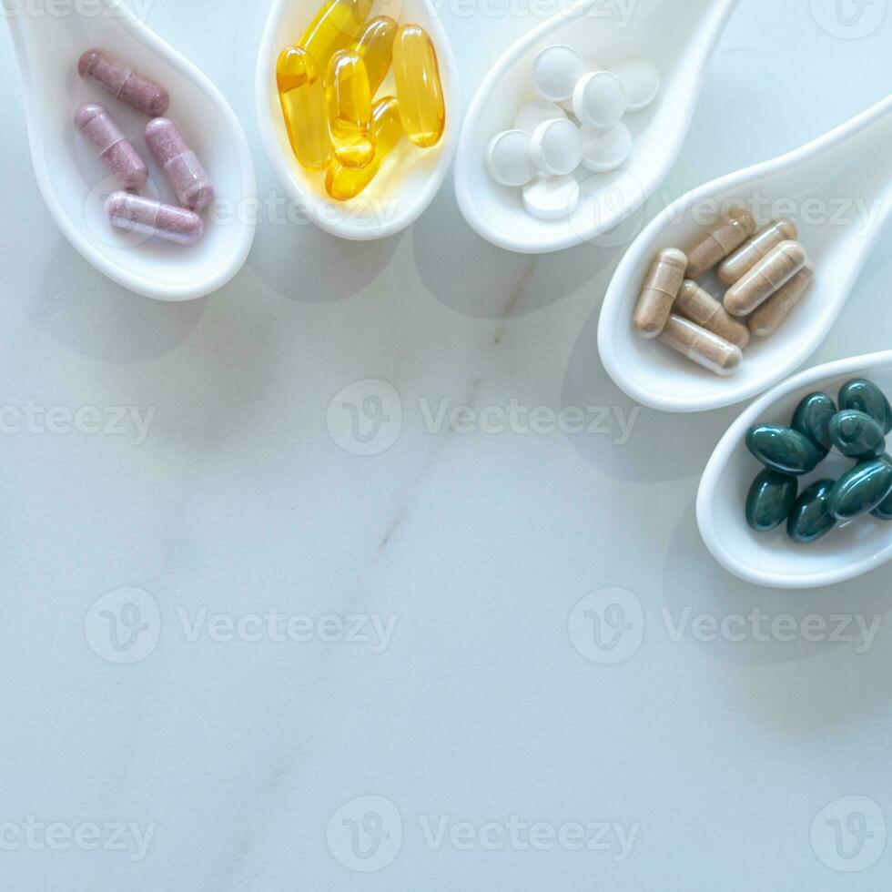 Medicine or vitamin in white spoons on white table copy space background. photo