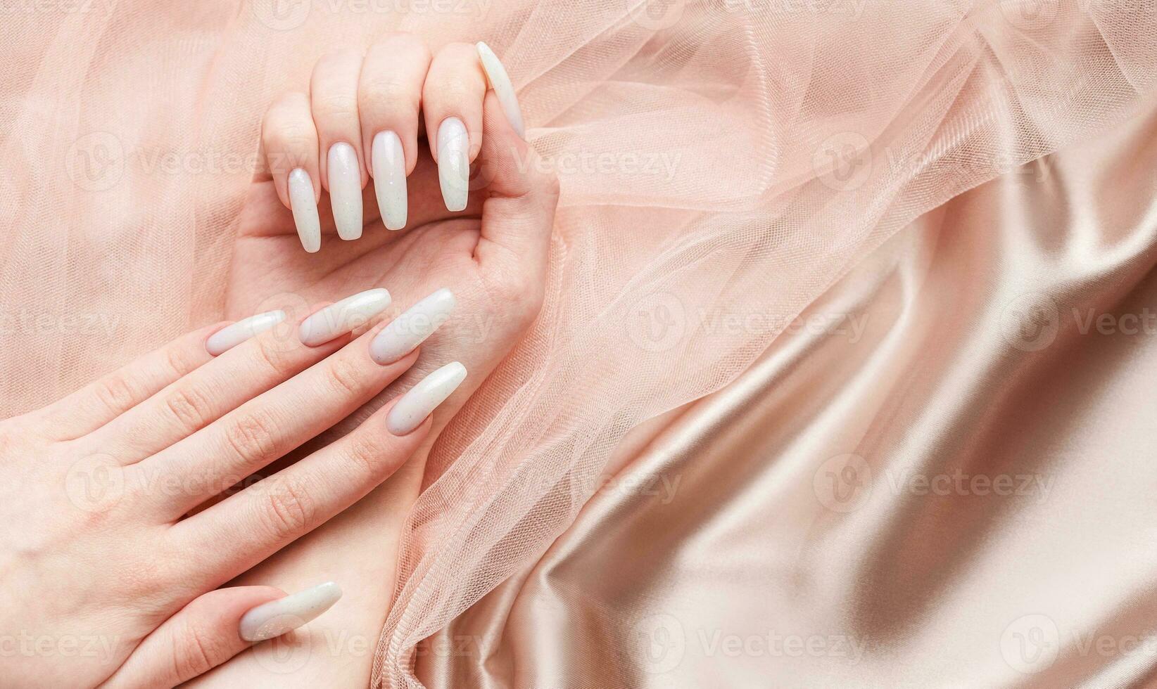 A woman's hands with a manicure on them, the nails are painted in a white color. photo