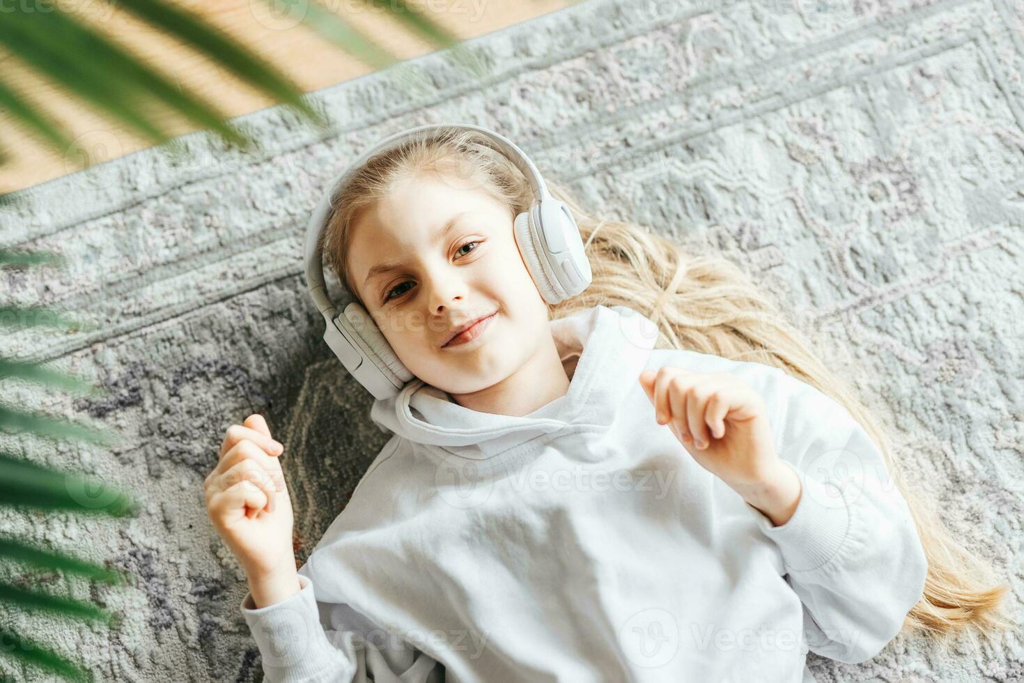 Little girl listening music lying on the floor photo