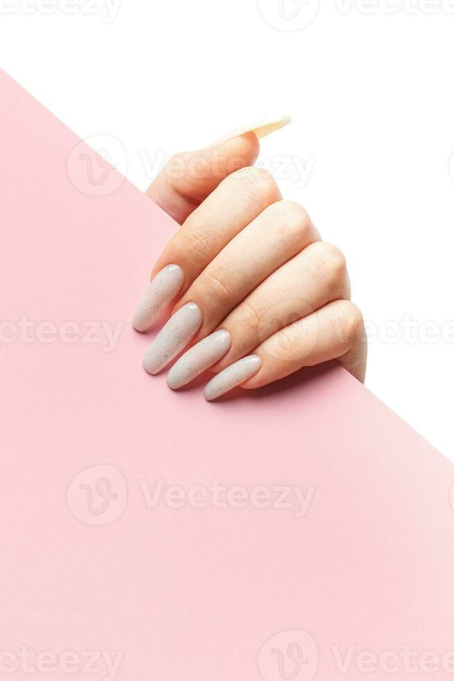 Manicured woman's hand holding pink paper. photo