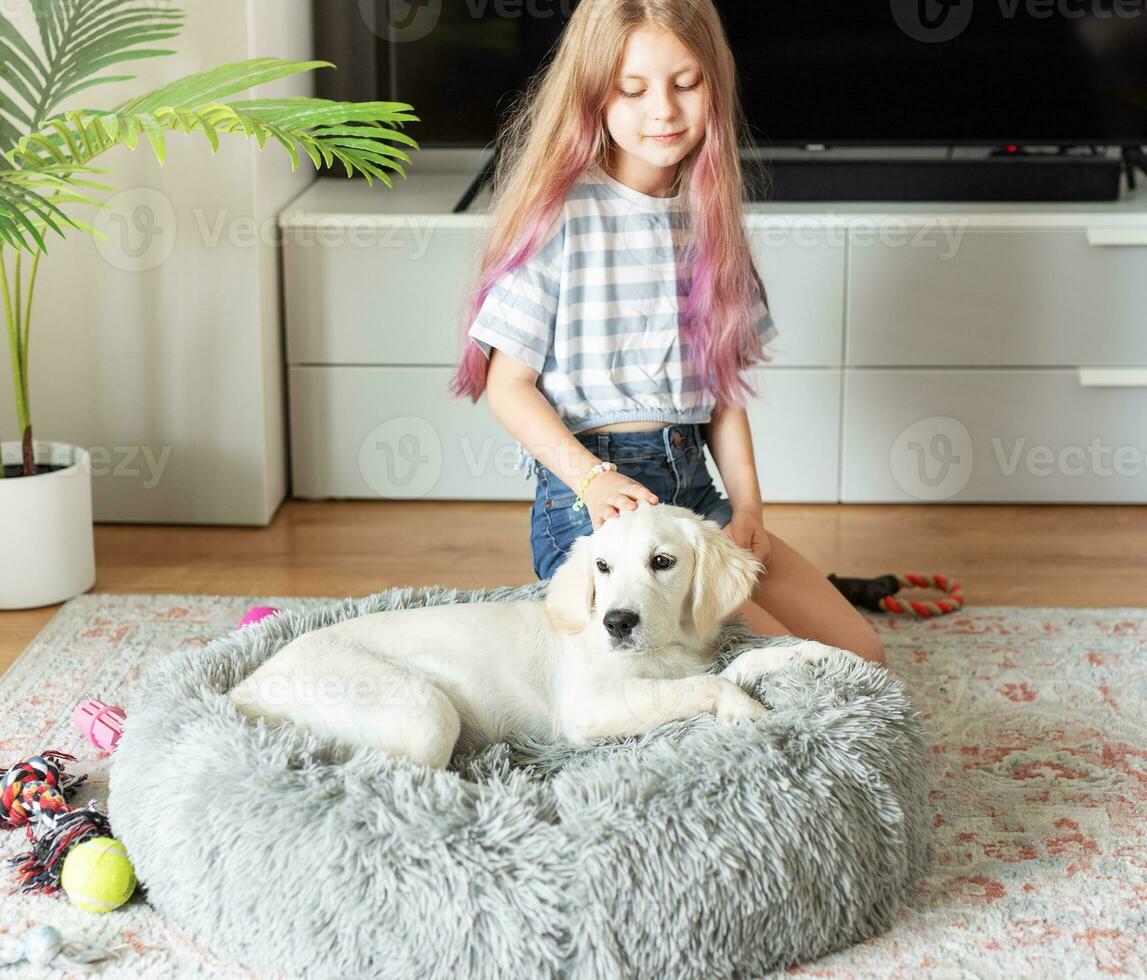 Little girl playing with a golden retriever puppy at home. photo