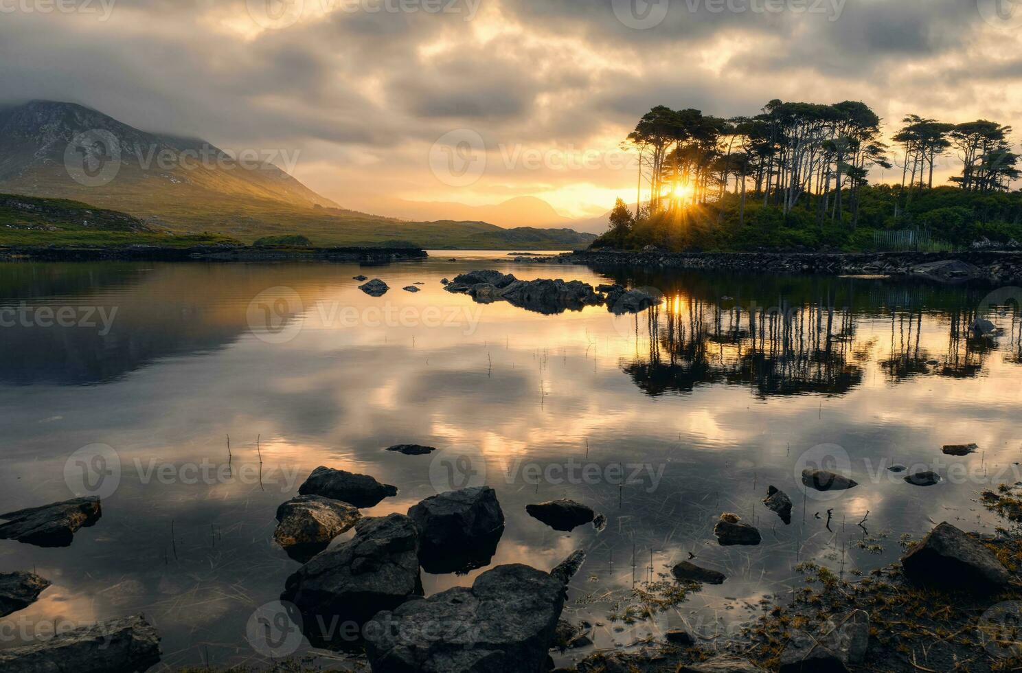 dramático nublado orilla del lago paisaje amanecer paisaje de doce pinos isla reflejado en agua rodeado por montañas a derryclare, Connemara nacional parque en condado galway, Irlanda foto