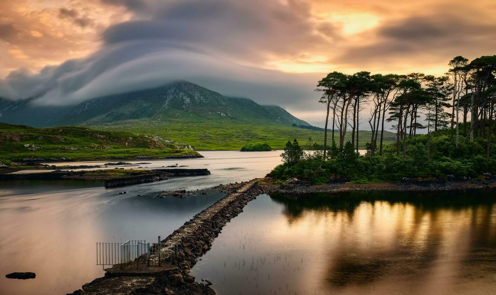 hermosa amanecer orilla del lago paisaje paisaje de doce pinos isla reflejado en agua rodeado por montañas a derryclare, Connemara nacional parque en condado galway, Irlanda foto