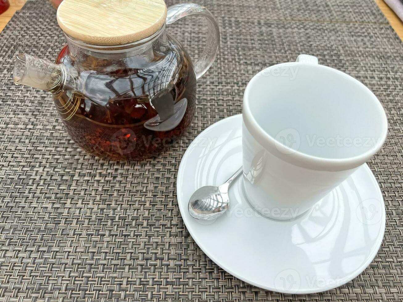 Teapot with tea and a cup on the table photo