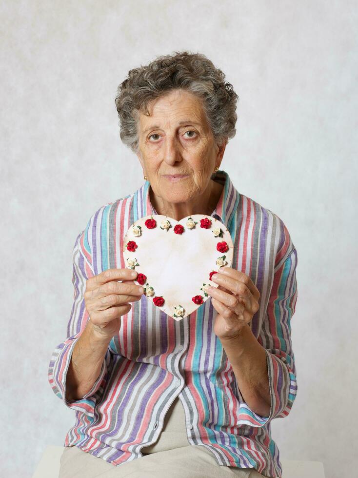 Old woman keeps a heart in her hands photo