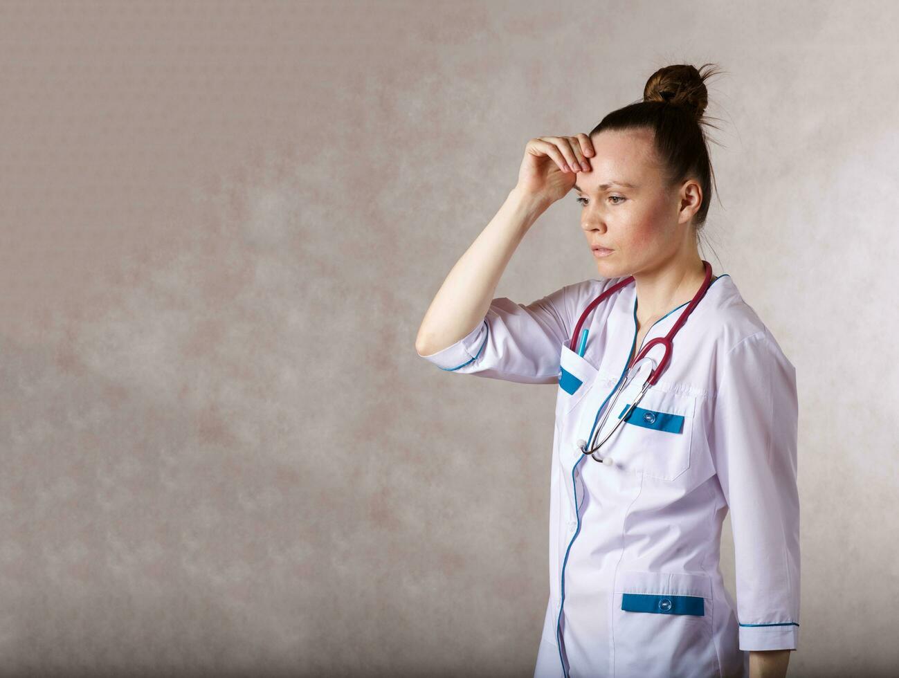 joven hembra médico vestido en un blanco médico uniforme arrepentimientos acerca de alguna cosa foto