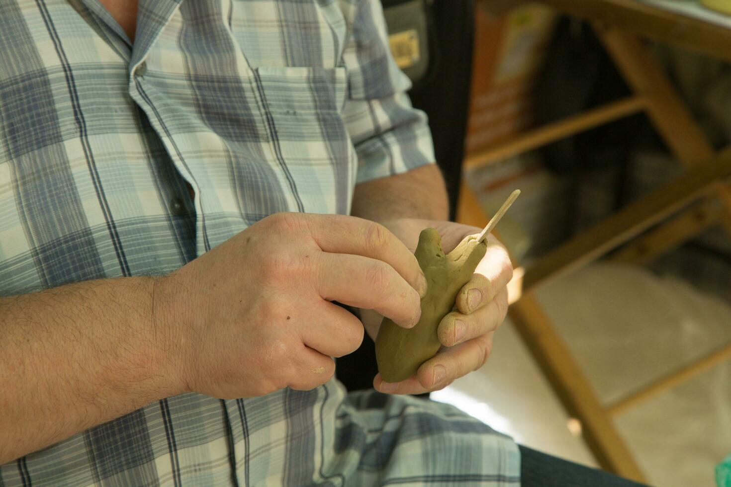 A man is modelling a figurine from clay photo