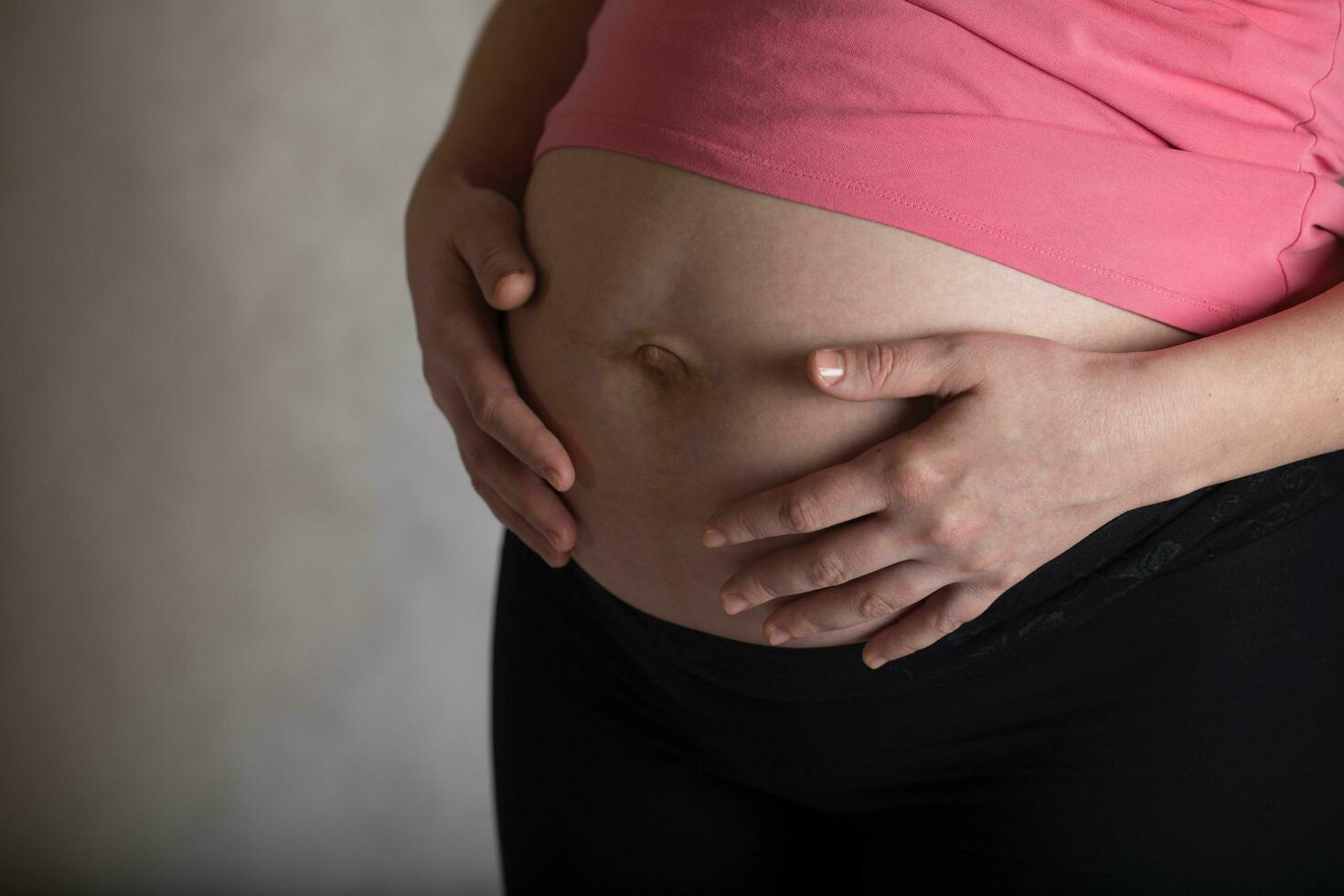 Young pregnant woman touches her belly. Dramatic light. photo