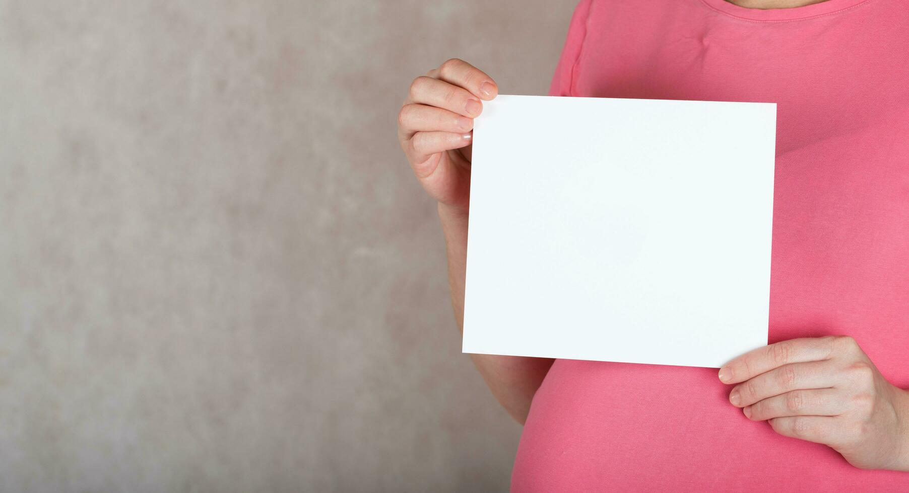 Young pregnant between 30 and 35 years old woman keeps a  blank white sheet of paper. photo